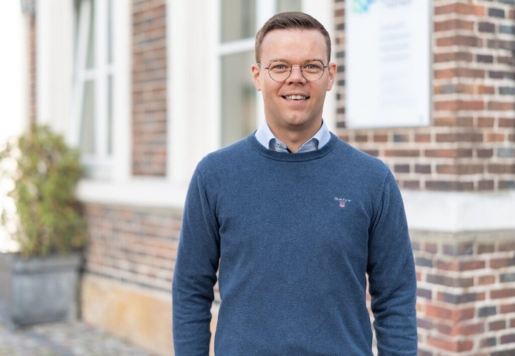 Partner Patrick Heitmann steht lächelnd vor dem Kanzleigebäude von Niehoff Schumacher + Partner in Horstmar.